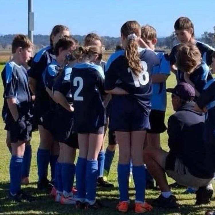 Children wearing blue soccer gear huddled in a circle